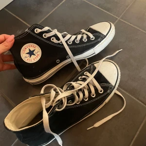 Svarta Converse All Star sneakers - Säljer ett par klassiska svarta Converse All Star sneakers med vita snören. Skorna har loggan på sidan och är aldrig använda. Stl 40 men passar även 39. Pris kan diskuteras 