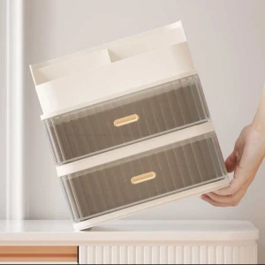 Smink låda  - Praktisk förvaringslåda i vit och transparent design med två utdragbara lådor och ett övre fack. Perfekt för att organisera smink eller småsaker på skrivbordet eller i badrummet. Lådorna har guldfärgade handtag för en elegant touch.