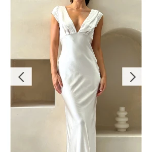 Champagne färgad långklänning med unik rygg - Elegant vit långklänning i satin med en v-ringad framsida och en stilfull öppen rygg. Klänningen har en knutdetalj bak och är ärmlös. Jag köpte denna på Billy J och klänningen är endast testad (prislapp kvar). Jag säljer den pågrund av att jag vill ha en annan färg på min balklänning och var för komplicerat att göra en retur🙃Köpte den för ca 1000 kr + frakt (300) + tull (700). Så la ungefär 2000 på den därav priset. Skriv om ni vill ha bilder när jag har den på ♥️Jag är i vanliga fall en S! 