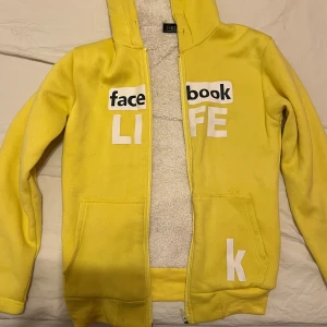Gul hoodie med text - Säljer en gul hoodie med texten 'facebook LIFE' på framsidan. Den har en dragkedja och är fodrad med mjukt, vitt material. Perfekt för en avslappnad stil. Super varm 