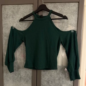 Grön ribbad offshoulder topp - Snygg grön ribbad topp med offshoulder-design och långa ärmar. Perfekt för en trendig look. Liten i storlek, är mer som en M.
