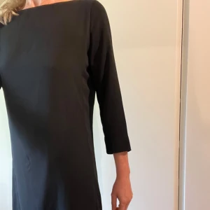 Svart Tommy Hilfiger klänning - Elegant svart klänning med trekvartsärm och en stilren dragkedja i ryggen. Perfekt för en minimalistisk look.