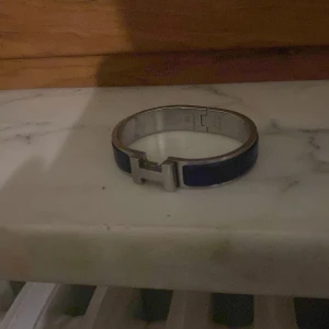 Blått Hermesarmband med silverdetaljer - Säljer nu mitt Hermesarmband. Kvitto eller bevis finns tyvärr inte. Armbandet är äkta men ganska slitet. Passar tjejer eller smalare killar
