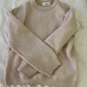 Rosa stickad tröja från H&M - Mysig rosa stickad tröja från H&M i storlek 134/140. Perfekt för kyliga dagar med sin klassiska design och ribbade muddar vid ärmslut och nederkant.