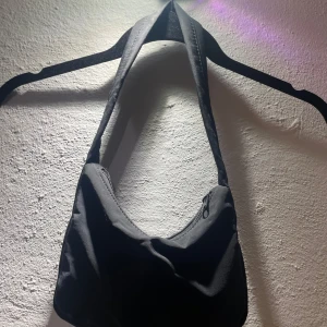 Svart axelväska med dragkedja - Snygg svart axelväska i syntetmaterial med praktisk dragkedja. Använd endast ett fåtal gånger och har ett jätte bra skick! 