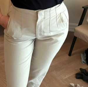 Beige kostymbyxor - Snygga beige kostymbyxor med hög midja och stilrena veck framtill. Fint skick 