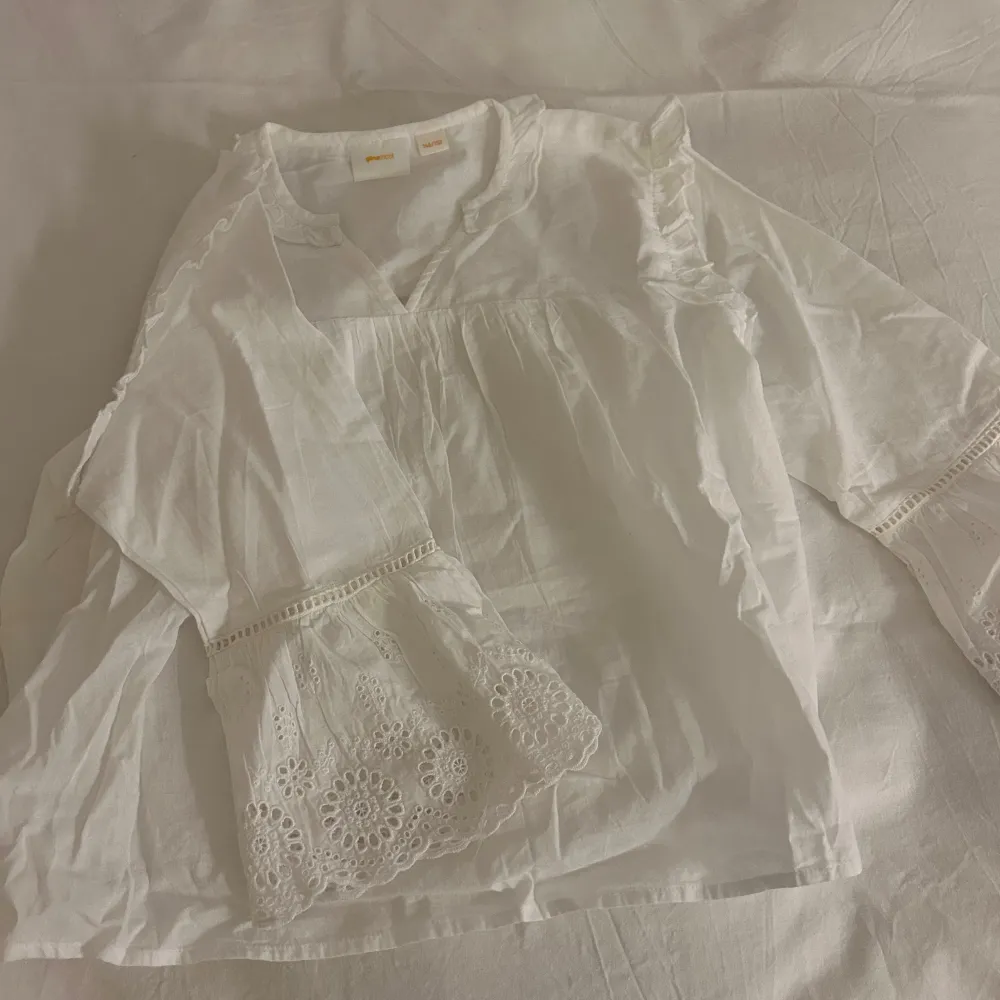 Säljer en söt vit blus från Gina Tricot med volangdetaljer och trekvartsärmar. Blusen har en v-ringad hals och spetsdetaljer på armarna. Storlek 146-152 och inte använd en enda gång!💕. Yläosat.