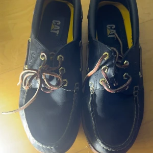 Bruna loafers från CAT - Säljer ett par bruna loafers från CAT med robust sula och snörning. Skorna har en klassisk design med slitstark konstruktion, perfekt för en avslappnad stil.