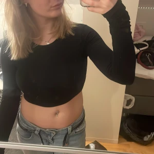 Svart croppad långärmad topp - Säljer en stilren svart croppad topp med långa ärmar. Väldigt skönt material och passar till alla möjliga stilar. Inga defekter