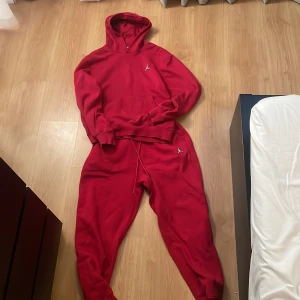 Röd hoodie och byxor från Jordan - Säljer en snygg röd hoodie från Jordan med det ikoniska logotypen på bröstet. Hoodien har en klassisk passform med långa ärmar och en praktisk huva. Perfekt för en sportig look eller avslappnade dagar.