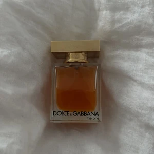 Parfym Dolce & Gabbana The One - Säljer en elegant parfym från Dolce & Gabbana, The One. Flaskan är rektangulär med en gyllene kork och innehåller en varm, bärnstensfärgad doft. Perfekt för den som vill ha en sofistikerad och tidlös doft. 50 Ml