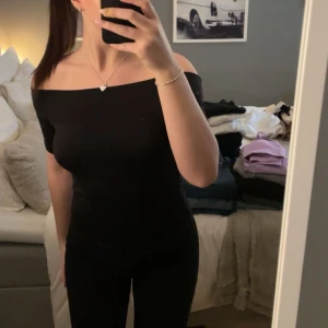 Svart offshoulder topp - Säljer en stilren svart offshoulder topp som sitter tight och framhäver figuren. Toppen är ärmlös och har en elegant design som passar till många olika outfits. Använd 1 gång💕