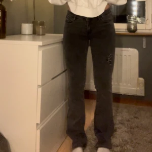 Grå jeans med slitningar - Snygga grå jeans i storlek XS med slitningar på låret. De har en bootcut-stil och är låmidjade. 