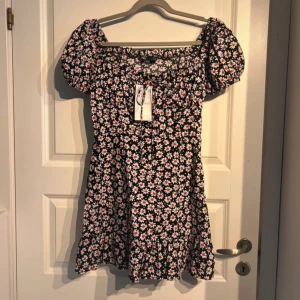 Kort blommig klänning från Zara - Säljer denna fina klänningen som tyvärr aldrig kommit till användning, prislappen sitter kvar. Det är en svart klänning med röda och vita blommor på. Den är i storlek M (normal i storleken)💕☺️