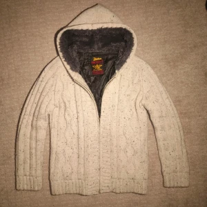 Stickad pälsfodrad cardigan  - Säljer en mysig stickad cardigan med fodring. Pälsfodrad i luvan och fodring i resten av tröjan. Extremt snygg med en stilren och unik design. Vit/beige färg med grå päls. Skriv vid minsta fundering! 