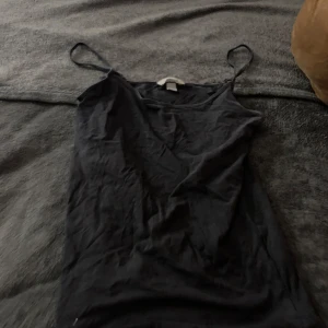 Svart linnetopp från Åhléns - Säljer en enkel och stilren svart linnetopp från Åhléns. Toppen har smala axelband och är perfekt för varma dagar. Passar bra till både jeans och kjol.