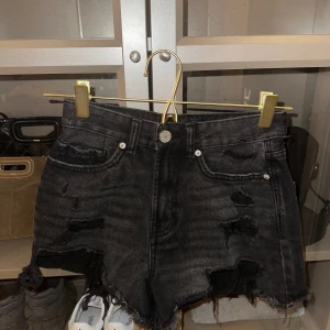 Svarta slitna jeansshorts - Snygga svarta jeansshorts med slitna detaljer och fransig kant. Perfekta för en avslappnad stil. De har en klassisk femficksdesign och knappgylf från new yorker 