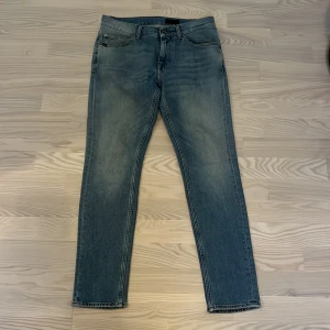 Tiger of sweden jeans  - Snygga blå jeans från Tiger of Sweden med en klassisk straight passform. De har en stilren design med fem fickor och en diskret läderpatch baktill. Perfekta för en avslappnad look. Mer info eller bilder hör av er!