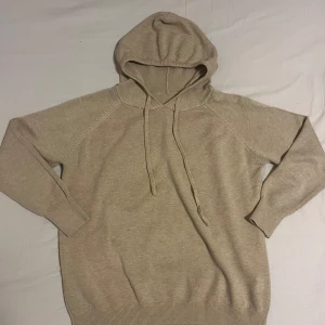 Beige merinoull hoodie  - Säljer en stilren beige hoodie med långa ärmar och justerbar huva. Merinoull hoodie i strl XS som bara är prövad och aldrig använd 