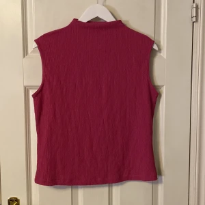 Rosa ärmlös topp från Anna Field - Säljer en snygg rosa ärmlös topp från Anna Field. Toppen har en hög krage och är tillverkad i ett ribbat material som ger en stilren look. Perfekt för att matcha med olika outfits.