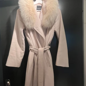 Hollieskappa - Beige kappa från Hollies i strl 34. Kemtvättad och jätte fin avtagbar äkta päls (racoon).  Midjeband både inuti och utanpå 