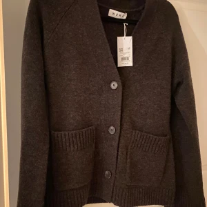 Wera stickad ullkofta WARD - ⭐️ Stickad kofta i ull ⭐️ Figursydd passform ⭐️Färgmatchad knappstängning fram ⭐️Två öppna fickor ⭐️Bred ribbstickning i ärmslut ⭐️V-ringning ⭐️Aldrig använd ⭐️Slutsåld online 