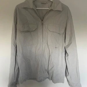 OVERSHIRT - En overshirt från YOKE i bra kvalitet och manchester tyg, med en fin blågrå färg. Tröjan är knappt använd och i bra skick. Storlek M men aningen större i storleken så passar nog dig som är 180+