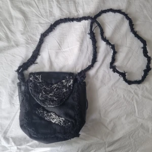 Svart läderväska - Var länge min "go to" väska men nu är det dags att sälja den vidare! Liten/Mellanstor svart läderväska med långt axelbnd. Väldigt rymlig för storleken, får plats med en vattenflaska! Är handgjort och i äkta läder. Obs litet hål på baksidan. Kostade orginellt 600kr