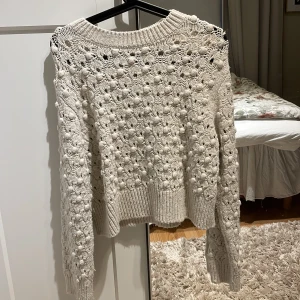 Beige stickad tröja med strukturmönster - Säljer en superfin beige stickad tröja med ett unikt strukturmönster. Tröjan har långa ärmar och en ribbad kant vid halsen, ärmsluten och nederkanten. Perfekt för höst och vinter när du vill vara både varm och stilren. Passar till både jeans och kjol