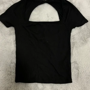 Svart ribbad topp - Säljer en stilren svart ribbad topp med korta ärmar och en unik öppen rygg. Perfekt för både vardag och fest! 🖤