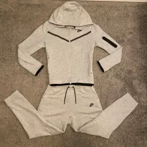 Nike tech fleece tracksuit i grå. Skick 9,5/10. Köpt från Nikes hemsida. Byxorna och hoodien för endast :- 799 nypris :- 2200. Storlek XL i barn men sitter som XS i herr. Går att köpa enskilda också. Skriv vid minsta fundering eller mer bilder.