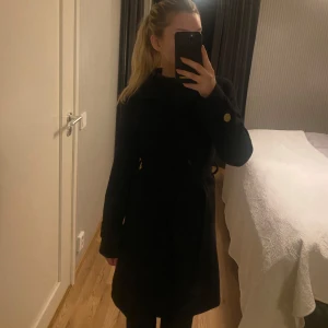 Svart långkappa  - Säljer en stilren svart kappa med knappar. Perfekt för höst och vinter. Den har en klassisk design med långa ärmar och en snygg passform. Skriv vid frågor och funderingar💕