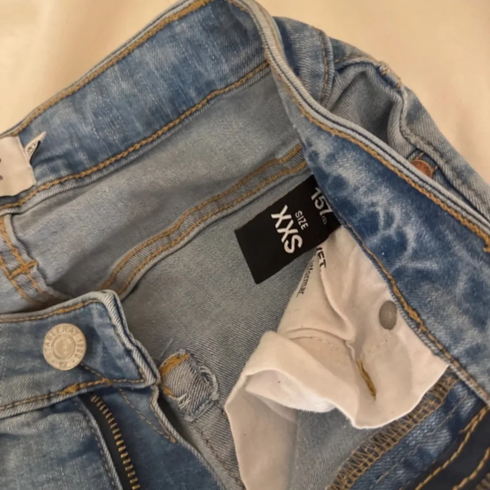 Säljer ett par ljusa jeans i storlek XXS från lager 157. De har en snygg slitning på knäna och en klassisk femficksdesign. Perfekta för en avslappnad vardagslook. Dragkedja och knapp framtill. Passar bra till både sneakers och boots!. Jeans & Byxor.