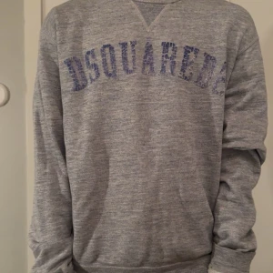 Grå sweatshirt från Dsquared2 - Säljer en unik grå sweatshirt från Dsquared2 i bra skick. Den är storlek L men sitter som M. Har ni någon fundering är det vara att höra av sig