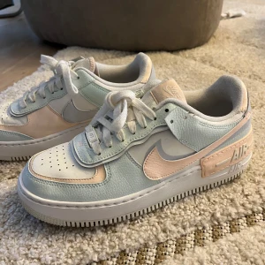 Nike Air Force i pastellfärger - Säljer ett par Nike Air Force i superfräscha pastellfärger! De har en mix av ljusblått och ljusrosa med vita detaljer. Skorna är i mycket bra skick och har klassisk snörning. Perfekta för att ge din outfit en färgklick! 🌸