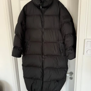 Svart dunjacka från Svea - Säljer en svart lång dunjacka från Svea i storlek medium. Jackan har en hög krage och dragkedja framtill. Perfekt för kalla vinterdagar med sin varma och puffiga design. Den är i mycket bra skick och redo för nya äventyr! Jag har lagat den vid ena fickan, kan skicka bättre bild om det behövs 💌