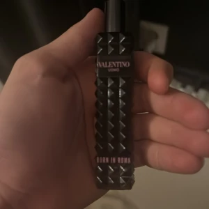 Valentino Born in Roma parfym - Säljer en snygg och elegant parfymflaska från Valentino, Born in Roma. Flaskan är svart med ett coolt nitat mönster som ger en lyxig känsla. Perfekt för den som vill ha en stilren och modern doft på hyllan. Passar både till vardags och fest!