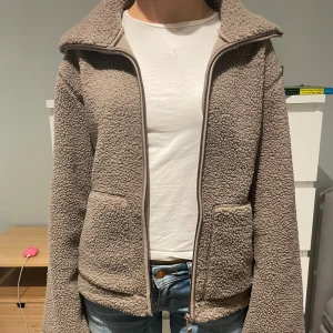 Beige teddyjacka hm - Mysig och eftertraktad teddyjacka från hm i storlek xs. Den är i den kalla bruna färgen. Den är aldrig andvänd och är alltså i toppskick. Jätte gosig och perfekt för höst och vinter!