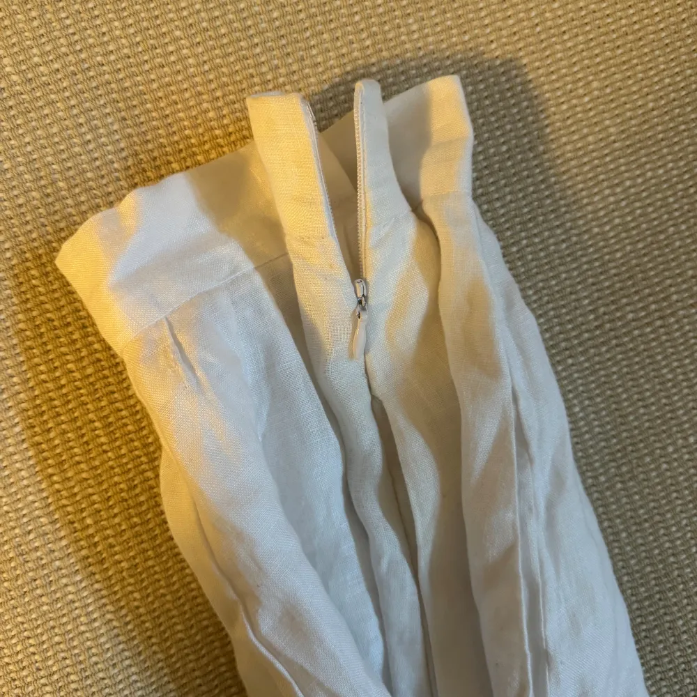 Säljer ett par vita linnebyxor från Posse. De är högmidjade med en dragkedja i sidan för enkel på- och avtagning. Perfekta för sommaren med sin luftiga och bekväma passform. Byxorna har en loose stil som ger en avslappnad look. Perfekta för både strandhäng och sommarfester!. Farkut & Housut.