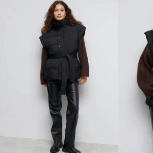 Svart dunväst med bälte - Säljer en snygg slutsåld svart dunväst från Gina tricot som är perfekt för höst och vinter. Västen har knappar och ett bälte i midjan för en justerbar passform. Den är både stilren och praktisk, idealisk för lager-på-lager-stil.