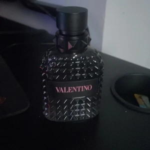 Valentino born in Roma 50ml  - Säljer en snygg parfymflaska från Valentino. Flaskan är mörk och har ett coolt nitat mönster som ger den en lyxig känsla. Perfekt för den som vill ha en stilren och elegant doft på hyllan. Passar både till vardags och fest!