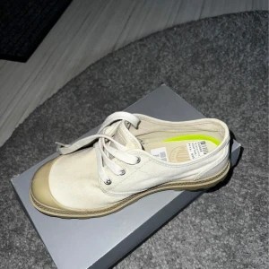 Palladium sneakers med snörning - Säljer ett par snygga beige palladium sneakers i mycket bra skick. De har en klassisk design med snörning och en ljusbrun sula. Perfekta för vardagsbruk och passar till det mesta i garderoben. Storlek är 37 och dom är aldrig använda, endast testade.