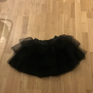 Svart tyllkjol från att. - Säljer en superfin svart tyllkjol från att. i storlek S. Perfekt för festliga tillfällen med sitt fluffiga lager av tyll som ger en voluminös look. Kjolen är kort och har en elastisk midja för bekväm passform. Passar perfekt till både vardag och fest! 🖤