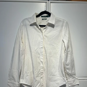 Vit skjorta från Ralph Lauren - Säljer en klassisk vit skjorta från Ralph Lauren i storlek M. Skjortan har långa ärmar och knappar framtill. Perfekt för både vardag och festliga tillfällen. 
