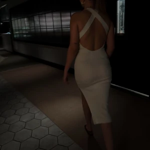 LXA klänning - En ljus beige klänning från LXA med en djup ryggringning och korsade band i ryggen. Klänningen är figursydd och har en slits i sidan. Den är väldigt stretchig i materialet vilket gör att ex jag som vanligtvis är storlek M endå kan ha den