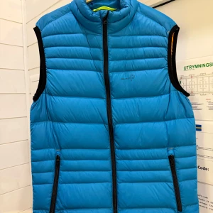 Blå dunväst från Pelle P - Säljer en snygg blå dunväst från Pelle P i storlek M. Västen har en dragkedja framtill och två praktiska fickor med dragkedjor. Perfekt för kyliga dagar och passar bra till både höst och vår. Den är i mycket bra skick och redo för nya äventyr!