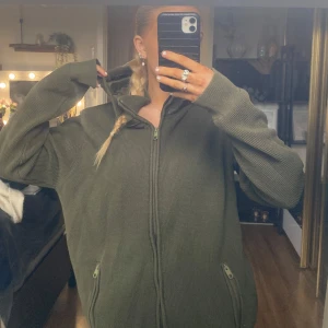 Olivgrön stickad hoodie - Säljer en olivgrön stickad hoodie från Peak Performance. Den har en dragkedja framtill och praktiska fickor med dragkedjor. Perfekt för kyliga höst- och vinterdagar. Den är i mycket bra skick och supermysig att ha på sig! Strl XXL köpt på herr