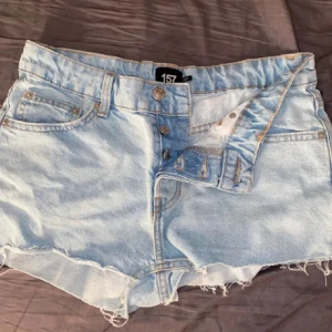 Ljusblå jeansshorts - Säljer ett par ljusblå jeansshorts från 157 i bra skick. De har en fransig kant och knappar framtill. Perfekta för sommardagar och avslappnade stunder. Passar till både t-shirt och linne! (LÅNADE BILDER). Dem är storlek xD men skulle passa någon med xxs också då dem är små i storleken. Köpta för 300