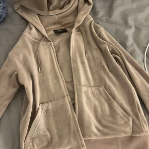 Beige hoodie från Juicy Couture - Säljer en supermjuk och snygg beige hoodie från Juicy Couture. Den har en dragkedja framtill och en broderad logga på bröstet. Perfekt för en chill dag eller när du vill vara bekväm men ändå stilren. 🧥✨