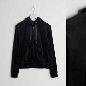 Svart velour hoodie - Säljer en supermjuk och bekväm svart hoodie i velourmaterial. Perfekt för mysiga dagar eller en avslappnad stil. Den har en dragkedja framtill och en praktisk huva med snören. Fickor på framsidan för extra komfort. Passar perfekt till höst och vinter!